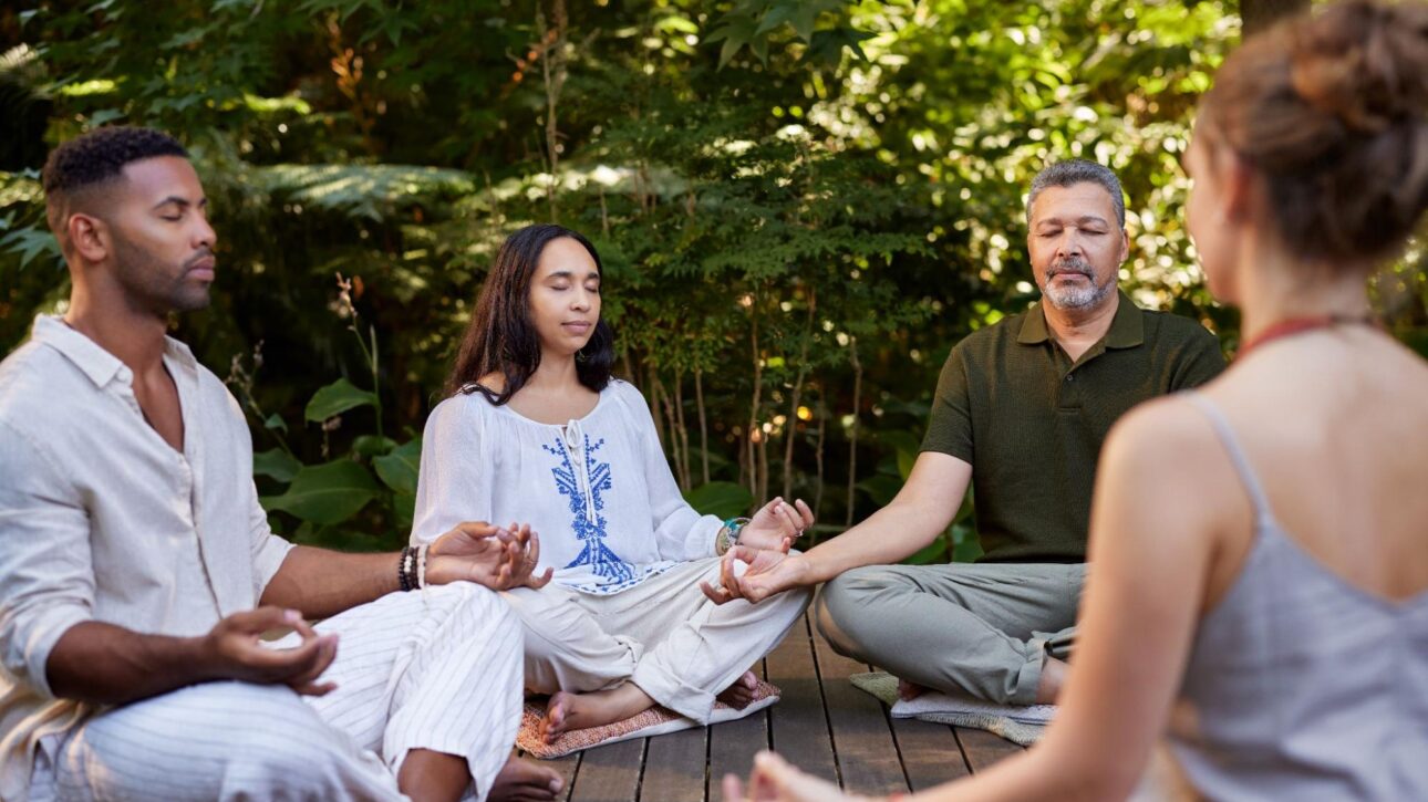 People practicing seated meditation during a yoga session in nature.