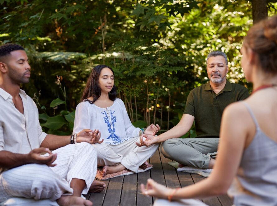 People practicing seated meditation during a yoga session in nature.