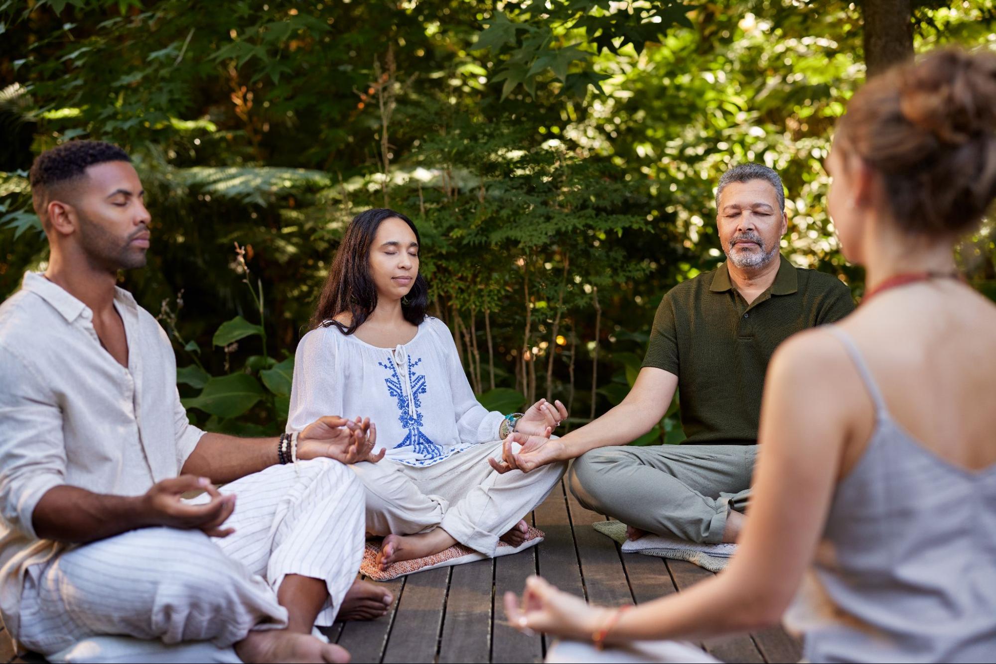 People practicing seated meditation during a yoga session in nature.