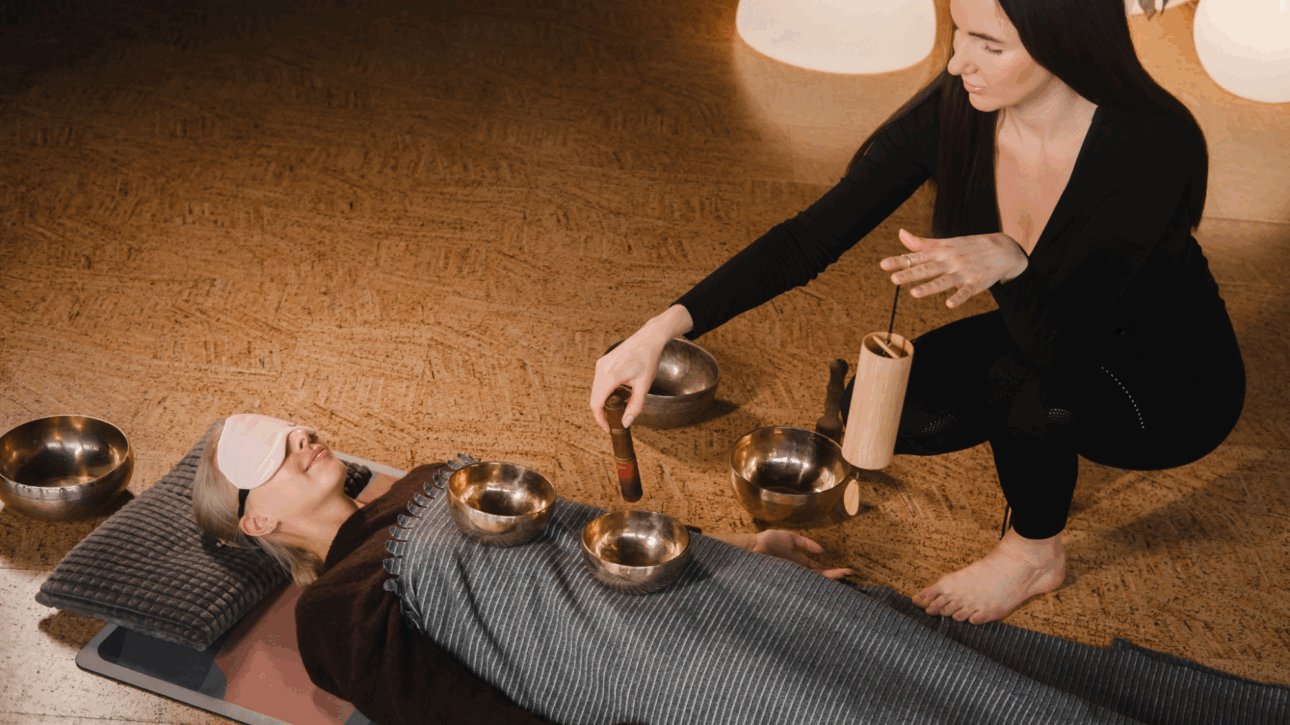 A woman performing a sound bath on a female client.