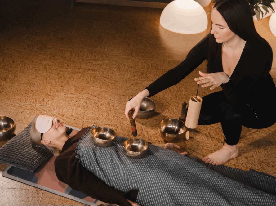 A woman performing a sound bath on a female client.